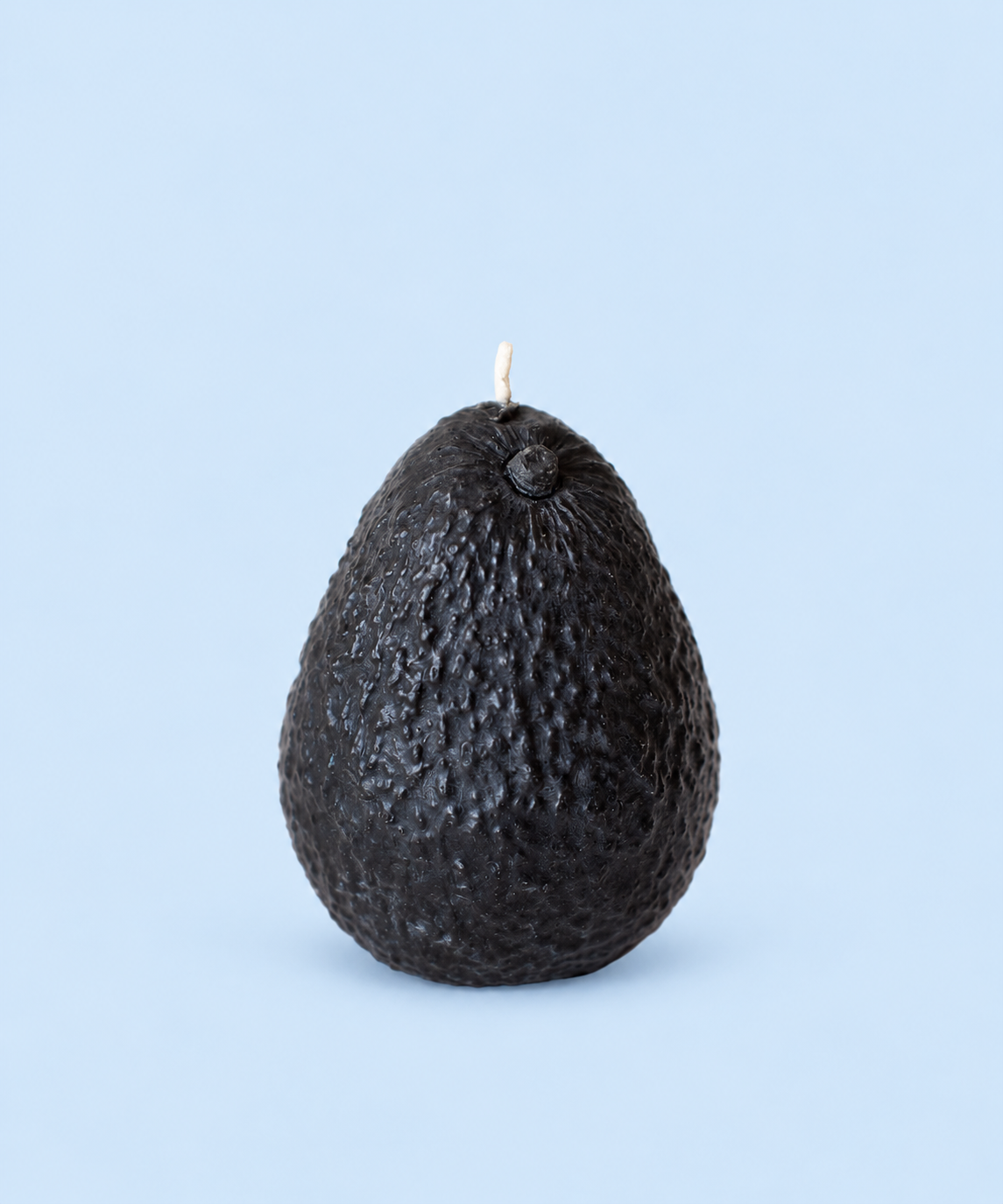 Avocado-shaped beeswax candle with a dark textured skin and cotton wick, handmade in Los Angeles