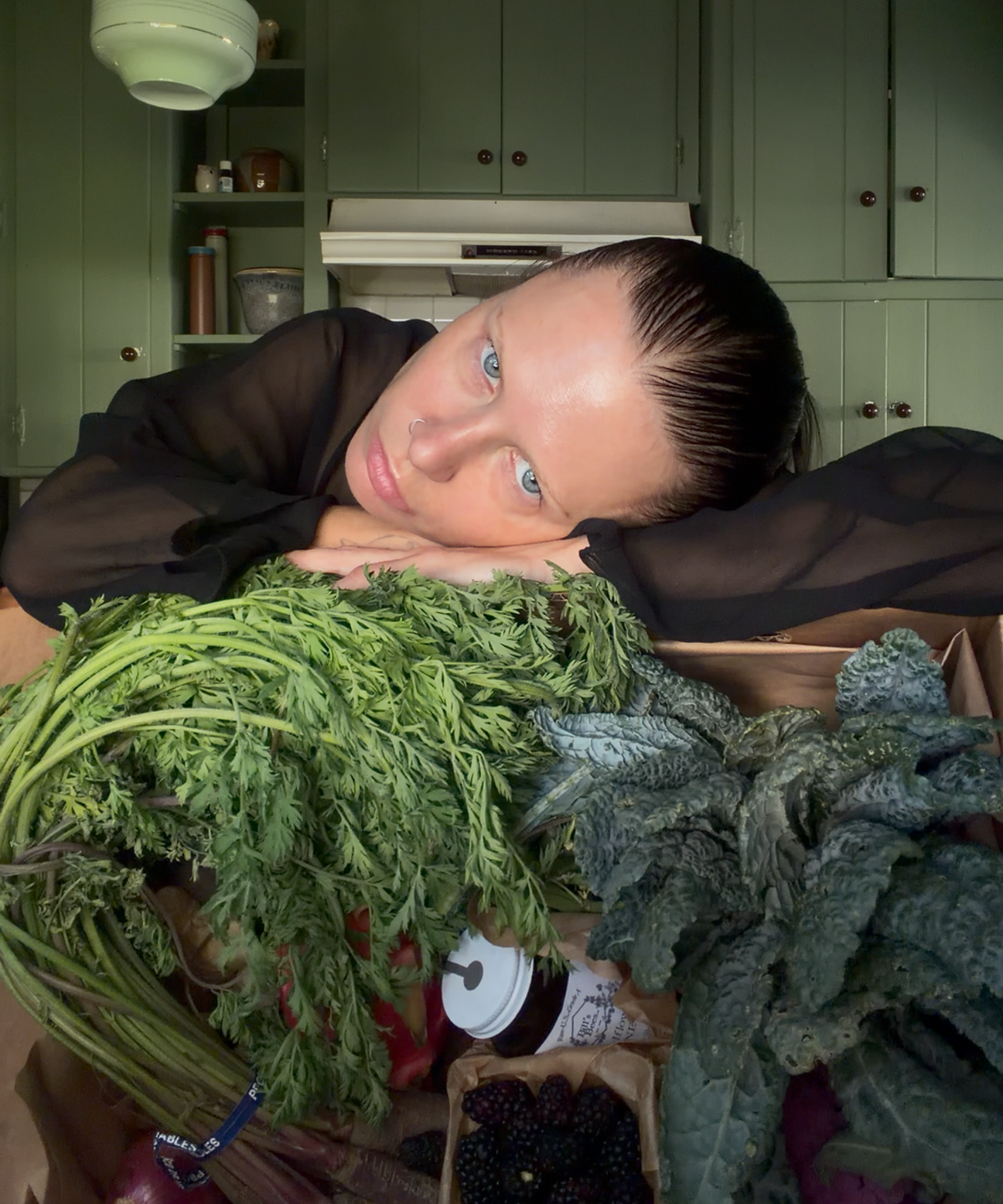 Courtney Trop of @alwaysjudging resting on a pile of fresh carrot greens from The Sexy Chef Box, a Market Mama farmers market produce box in Los Angeles