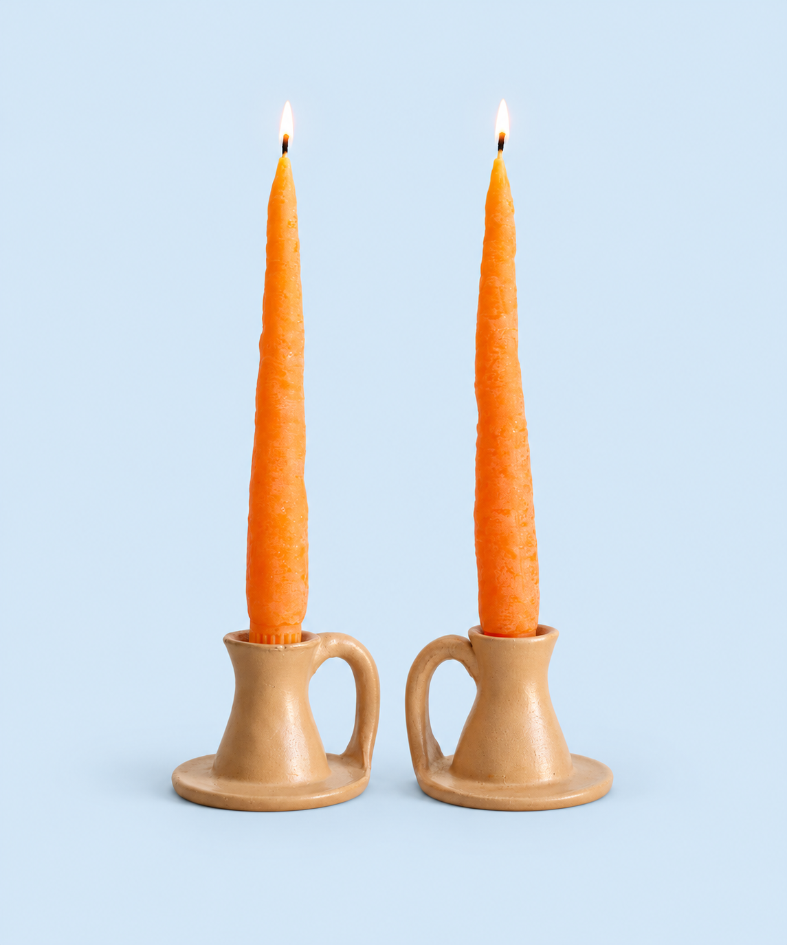 Two orange carrot-shaped beeswax taper candles, handmade in Los Angeles